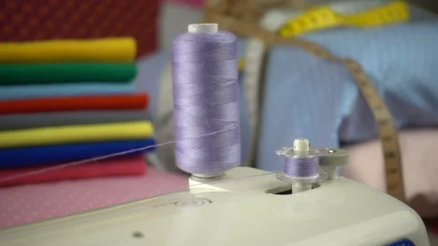 Thread is unwound from the reel during sewing to other coil in slow motion. Sewi Stock Footage 100200554