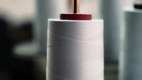 The thread is unwound from the spool while sewing by a seamstress on a sewing Stock Footage 199307471
