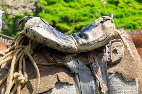 Threadbare old saddle on a shepherd's horse, handmade saddle of a peasant she Stock Photos