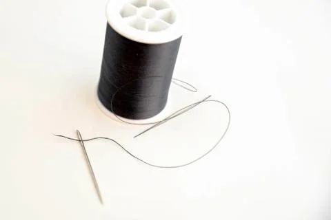Threaded needle and black spool of thread Foto stock