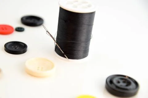 Threaded needle, black thread spool and buttons Stock Photos