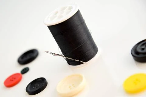 Threaded needle, black thread spool and buttons Stock Photos