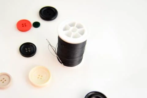 Threaded needle, black thread spool and buttons Stock Photos