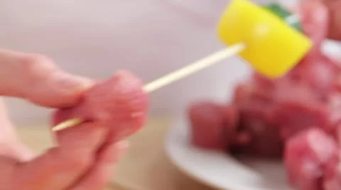Threading cubes of meat and vegetables onto a wooden skewer Stock Footage 24664124