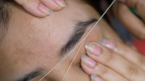 Threading eye brows of a young Indian female in beauty parlour Stock Footage 116664268