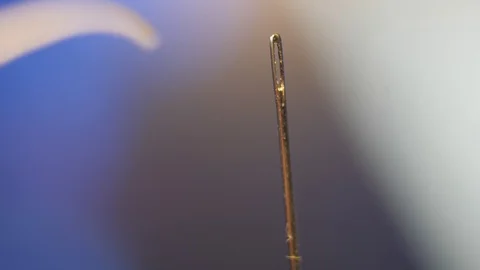 Threading the eye of a needle. Pulling the thread into the needle eye of the Stock Footage 87471340