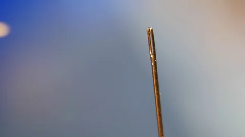 Threading the eye of a needle. Pulling the thread into the needle eye of the Stock Footage 87951620