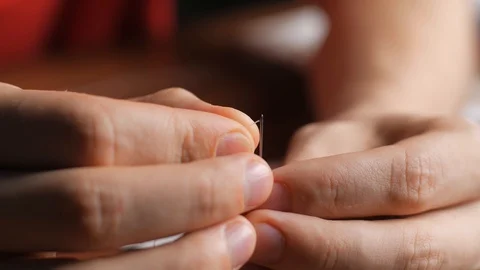 Threading the eye of a needle. Pulling the thread into the needle eye of the. Video stock 128363576