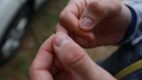 Threading a fishing line through a hole close up on hands threading needle Vídeo Stock 107614520