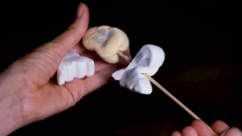 Threading Halloween ghost and pumpkin-shaped marshmallows onto a wooden skewer 스톡 동영상 347382721
