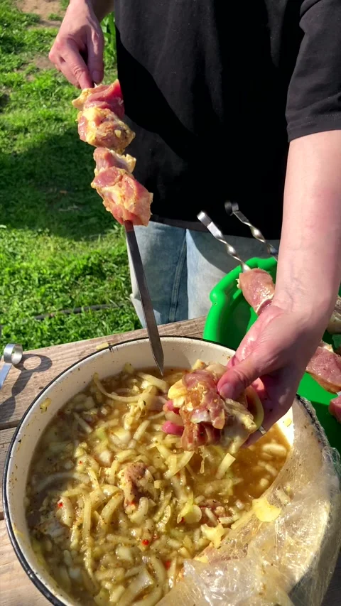 Threading marinated raw meat onto a metal skewer for barbecue. Stock Footage 339976323