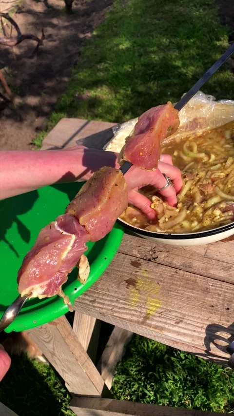 Threading marinated raw meat onto a metal skewer for barbecue. Stock Footage 339976325