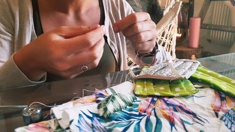 Threading a needle and hand sewing a face mask made from old clothes - Stock Footage 128425724