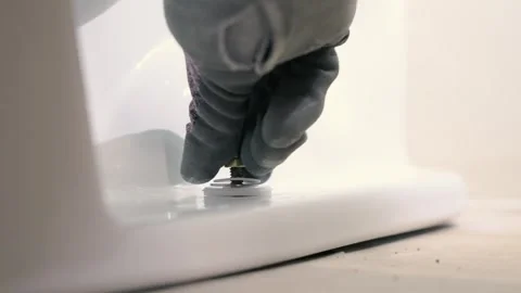 Threading a nut onto the side of a toilet bowl Stock Footage 281993330