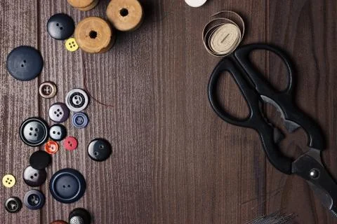 Threads buttons and needles on brown wooden table Stock Photos