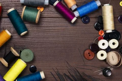 Threads buttons and needles on the brown wooden table Stock Photos