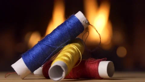 Threads. Colored spools of thread lie on the table against the firelight. Video stock 143637933