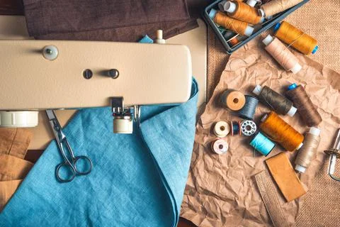 Threads of different colors, scissors, fabrics on the background of a blurred Stock Photos