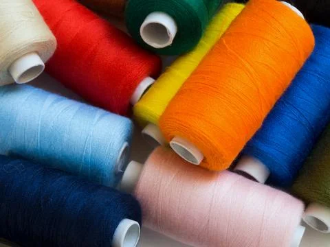 Threads of different colors on spools, irregularly scattered Stock Photos