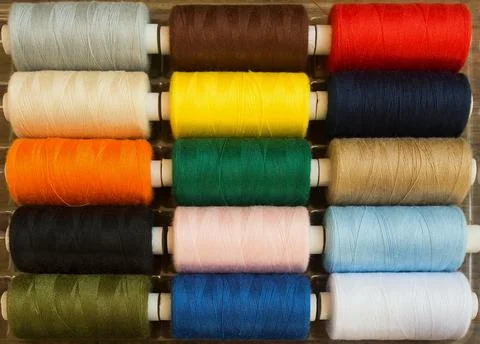 Threads of different colors on spools, regularly arranged in rows Stock Photos