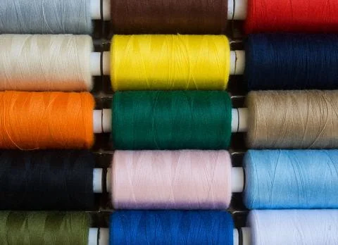 Threads of different colors on spools, regularly arranged in rows, 2 Stock Photos