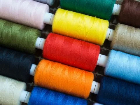 Threads of different colors on spools, regularly arranged in slantig rows Stock Photos