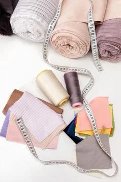 Threads, flaps of fabric, centimeter and rolls of fabric on a white table. se Stock-Fotos