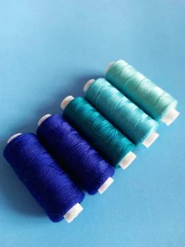 Threads for sewing in blue colors on a light blue background Stock Photos