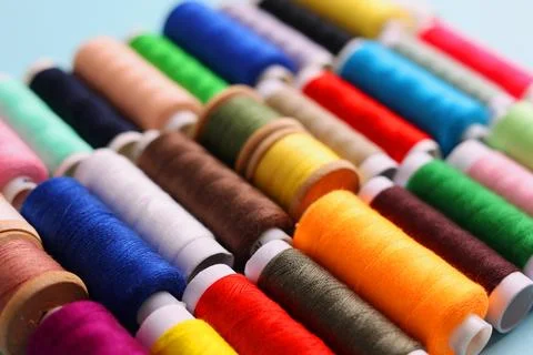 Threads for sewing in different colors on a colored background Stock Photos