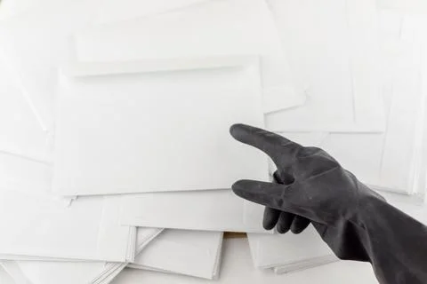 The threat in an envelope: People in protective impermeable gloves indicates  Stock Photos