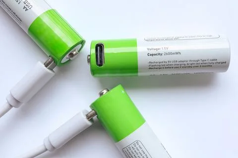 Three AA batteries are connected to the USB Type C cable on the table.  Stock Photos