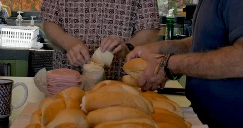 Three active retired seniors making ham and cheese sandwiches together Stock Footage 95149836