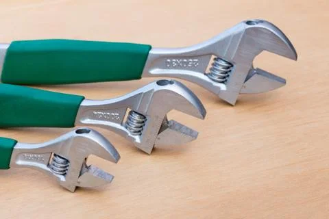 Three adjustable wrenches in row on wood Stock Photos