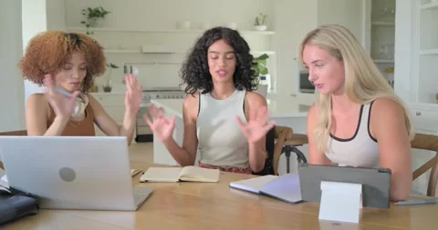 Three adult women doing task in kitchen, center starting notes, others using Stock Footage 341241910