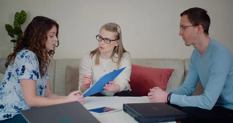 Three adults discussing a document in a bright living room Stock Footage 347413766