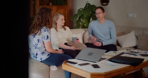 Three adults talking on a sofa in a cozy living room Video stock 347414288