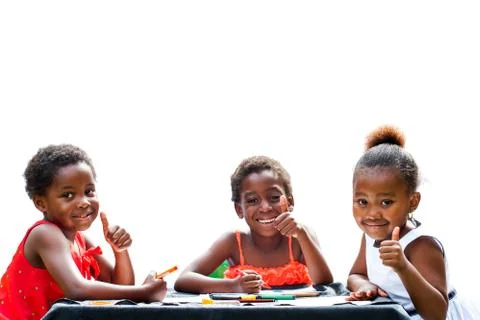 Three african girls doing thumbs up at table. Stock Photos