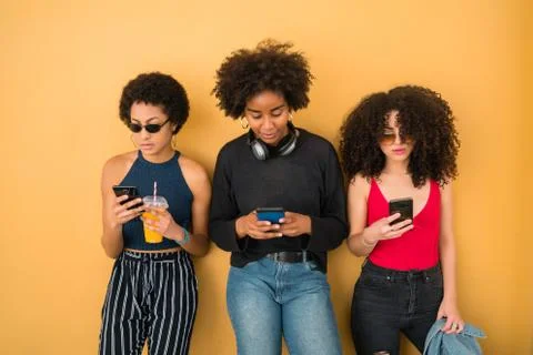 Three Afro friends using their mobile phone. Stock Photos