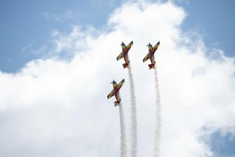 Three airplanes in the sky within clouds performing acrobatics during an air Stock Photos