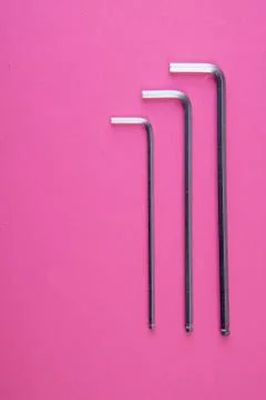 Three allen wrenches sorted by size on pink Stock Photos