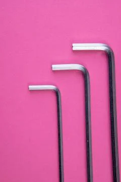 Three allen wrenches sorted by size on pink Stock Photos