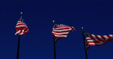 Three American Flags fluttering against dark blue sky Stock Footage 56741879