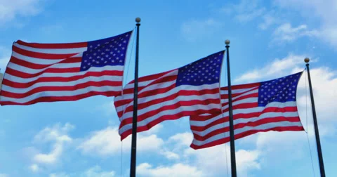 Three American Flags fluttering against light blue sky Stockbeeldmateriaal 57477205