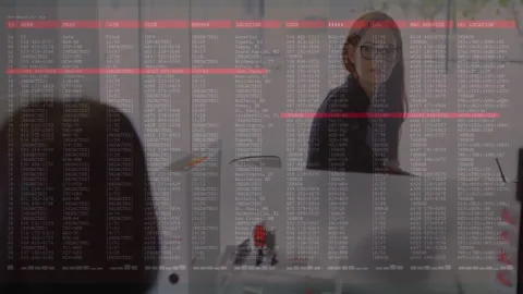 Three analysts reviewing data code on glass wall in tech office, highlighting Stock Footage 308572193