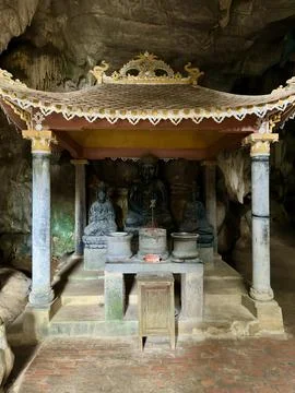 Three ancient stone Buddha statues residing in a shrine deep inside Stock Photos