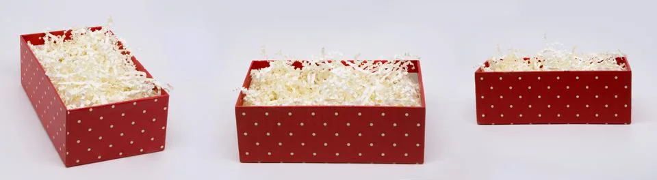 Three angles of a paper-filled red gift box isolated on a light background. Stock Photos