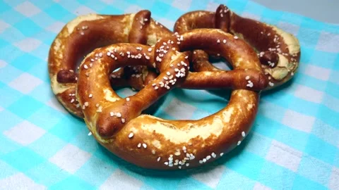 Three appetizing bavarian pretzel on blue cloth, rotating video Stock Footage 235535635