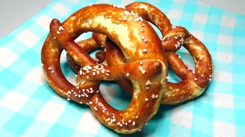 Three appetizing bavarian pretzel on blue cloth, rotating video Stock Footage 235535702