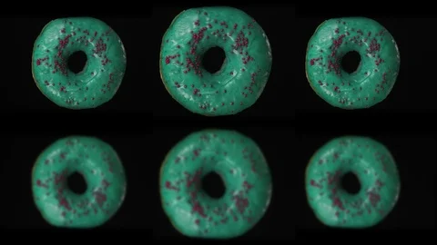 Three appetizing blue donuts rotate on a black background. Donuts spin on a Stock Footage 125831534