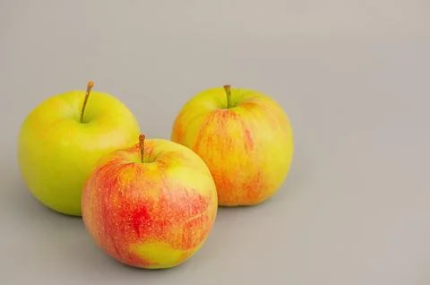 Three apples on a gray background. Stock Photos